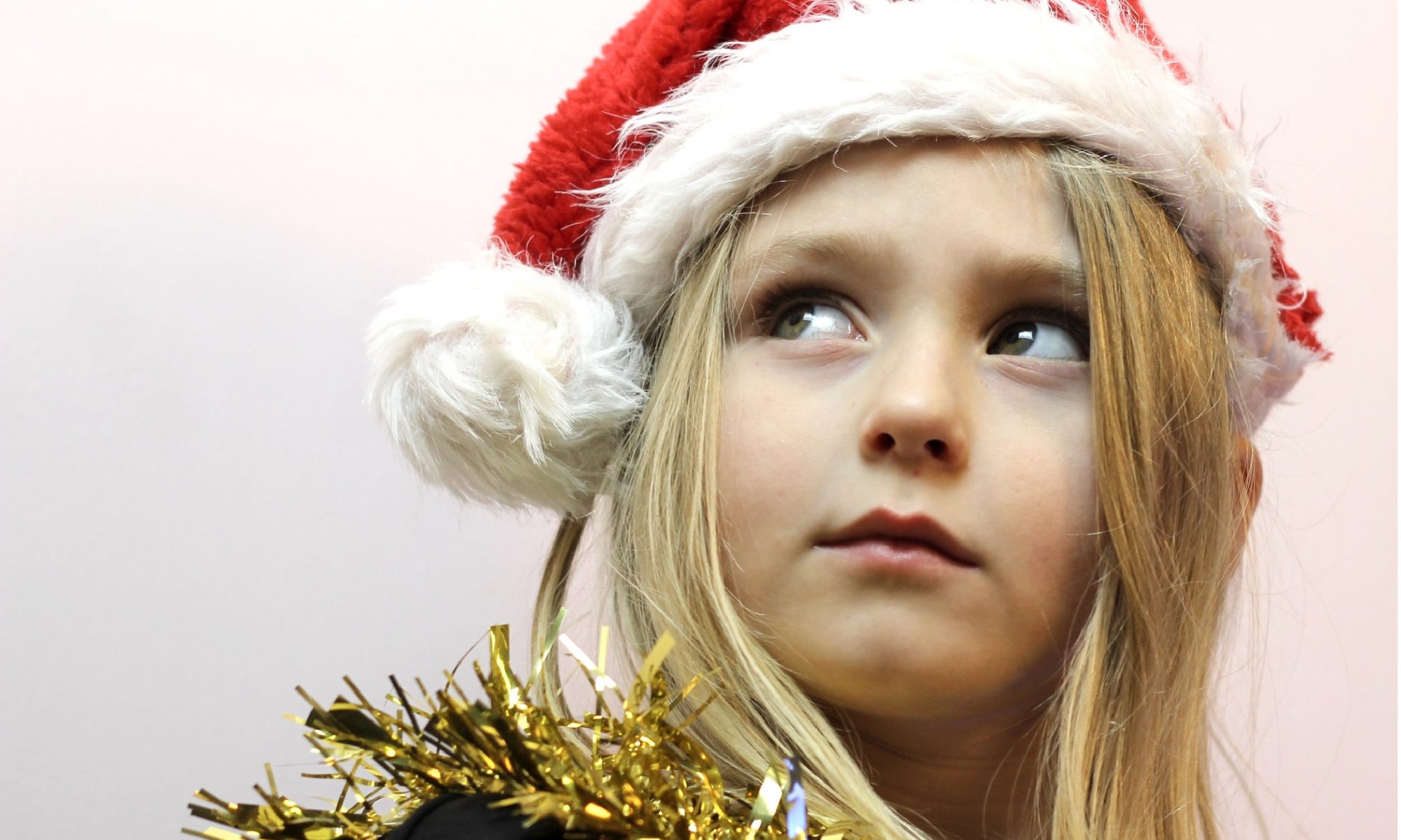 Little girl with santa hat on and tinsel around neck